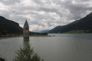 der Kirchturm von Alt-Graun im Reschensee, im Hintergrund die Ortlergruppe