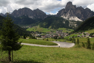 Blick über die Nordrampe des Passo di Campolongo auf Corvara, dahinter v. l. n. r.: Sas Ciampac, Sas Ciampei und Sassongher